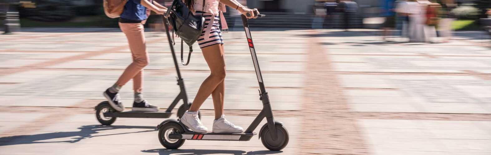 Girlfriends riding e-scooters in the city